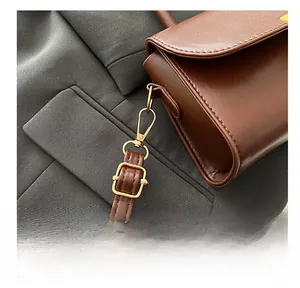 Close-up of premium brown leather bag showing golden metal hooks and adjustable strap