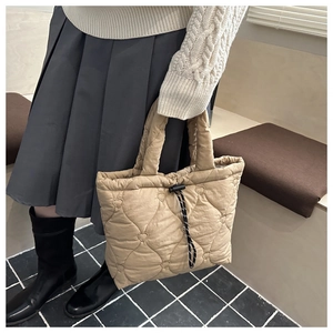 Detail of light brown heart quilted puffer tote bag with black drawstring closure