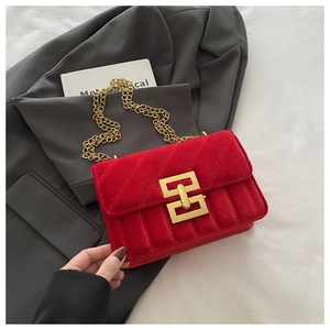 Detail of red suede crossbody bag with gold chain strap and geometric metal lock
