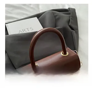 Detail of vintage brown leather handbag featuring round handle and gold metal rings