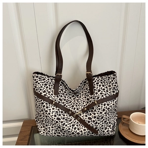 Détail d'un sac cabas à imprimé léopard avec poignées en cuir marron et boucles dorées