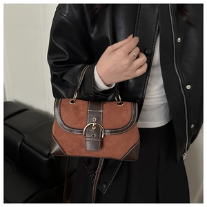 Detail of vintage brown suede and leather handbag with white stitching and gold horseshoe buckle