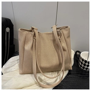 Close-up of beige canvas tote bag showing coarse texture and metal ring reinforcements