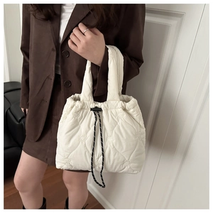 Close-up of white quilted tote bag featuring heart embroidery and drawstring closure