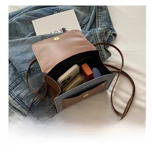 Detail view of denim and brown leather crossbody bag showing inner storage capacity