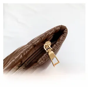 Détail d'une fermeture éclair dorée et d'un tissu matelassé marron sur un sac à main