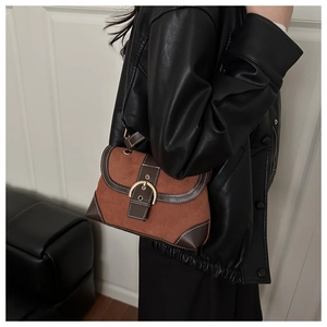 Detail view of vintage brown suede shoulder bag with gold horseshoe buckle and white stitching
