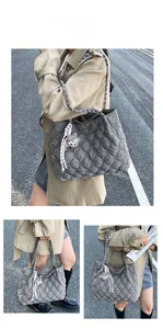Macro shot of grey quilted hobo bag with braided strap and cute plush bear charm detail