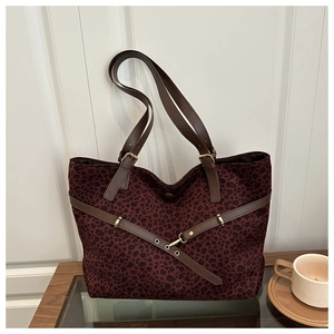 Détail du grand cabas léopard bordeaux avec anses en cuir marron et boucle dorée