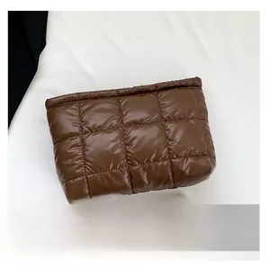 Gros plan de la pochette matelassée café en nylon à côté d'un smartphone pour échelle