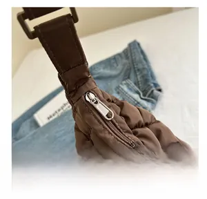 Détail de la fermeture éclair et du tissu en nylon matelassé marron foncé d'un sac cabas