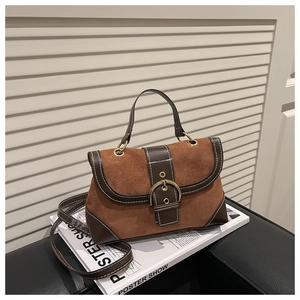 Close-up of vintage brown suede and leather handbag with large gold metal buckle detail