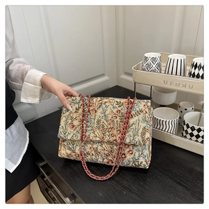 Detailansicht des Blumenstickerei-Stoffs und der roten Kette an der Klapptasche