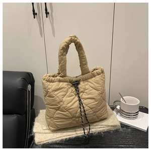 Detail of khaki quilted tote bag with heart patterns and woven drawstring closure