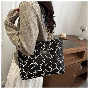 Détail d'un sac cabas noir avec broderie étoile blanche et bandoulière chaîne dorée