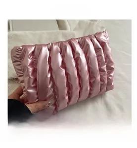 Detailed close-up of pink metallic pleated fabric and quilted texture on clutch bag