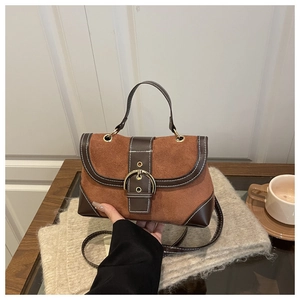 Detail of a brown suede handbag with a gold D-ring buckle and white contrast stitching