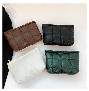 Vue détaillée des trousses à maquillage matelassées en noir, blanc, marron et vert
