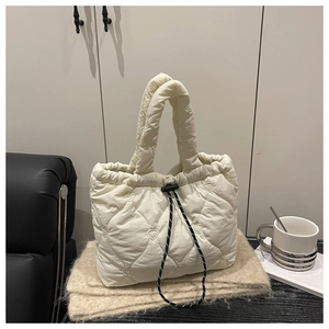 Detail of white quilted tote bag featuring heart pattern embroidery and drawstring closure