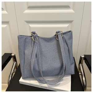 Detail view of blue denim tote bag featuring twill fabric and gold metal rings