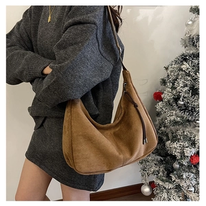 Dettaglio di borsa hobo grande in pelle scamosciata marrone con zip indossata dal modello