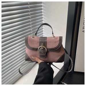 Detail of pink faux suede handbag with brown trim and gold horseshoe buckle closure