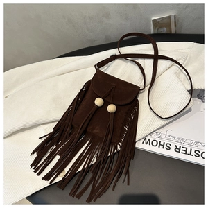 Détail d'un sac bandoulière en daim marron rétro avec de longues franges et perles