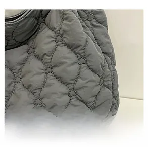 Close-up of grey quilted shoulder bag featuring heart-shaped stitching and fine fabric
