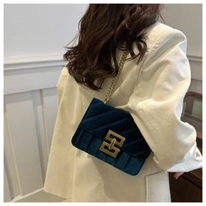 Detail view of peacock blue velvet shoulder bag with gold chain and geometric lock