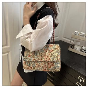Details von floralem Jacquard-Stoff und Metallkette an einer Vintage-Unterarmtasche