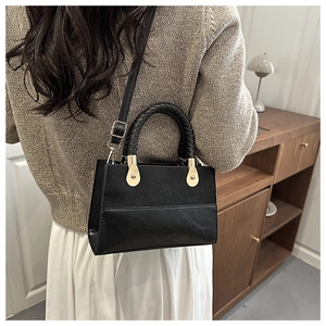 Close-up of black PU leather handbag with woven handle and gold hardware detail