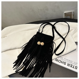Détail d'un sac bandoulière en suédine noire avec des franges et des perles en bois