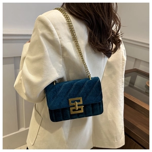 Detail of dark blue velvet crossbody bag with gold chain and quilted stitching design