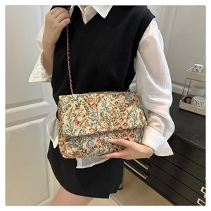 Detailansicht der floralen Stickerei-Handtasche mit rotem Leder-Kettenriemen-Detail