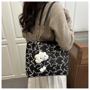 Détail du sac cabas noir avec broderie d'étoiles, chaîne dorée et breloque nuage