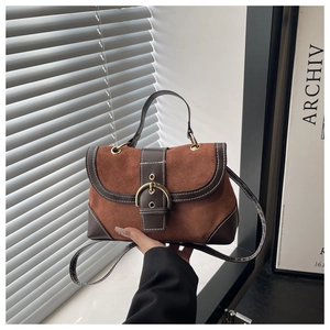 Close-up of vintage caramel suede and dark brown leather contrast handbag with metal buckle