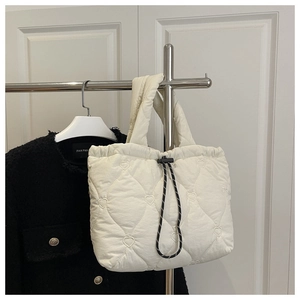 Close-up of white quilted tote bag featuring heart embroidery and drawstring closure