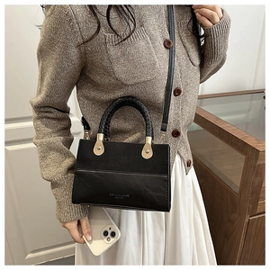 Detail of contrast stitch handbag with woven handle and gold teardrop hardware