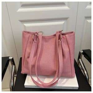 Close-up of woven pink and white tote bag with sturdy straps and gold hardware