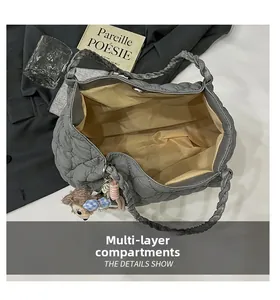 Detail of grey quilted tote bag featuring multi-compartment interior and woven handle