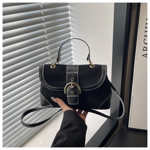 Detail of black vintage handbag with contrast stitching and golden hardware buckle
