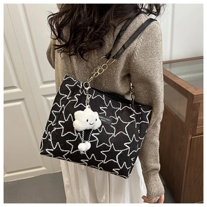 Détail du sac cabas noir avec broderie étoile, bandoulière chaîne et charme nuage en peluche