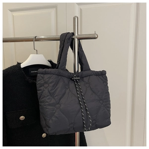 Detail of black quilted handbag featuring heart embroidery and woven drawstring closure