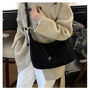 Dettaglio borsa a tracolla in pelle scamosciata nera con un cappotto di lana beige