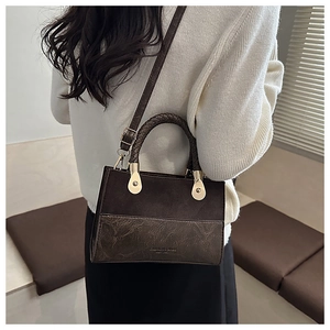Detail of vintage suede crossbody bag with woven handles and distressed leather texture