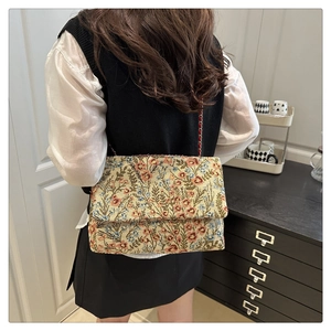 Detail der floralen Jacquard-Schultertasche mit Metallkettenriemen an einem Model