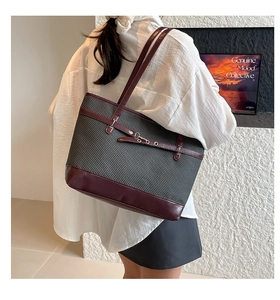 Close-up detail of grey woven tote bag with burgundy leather trim and metal buckle