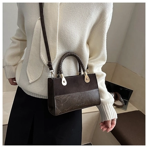 Detail of vintage two-tone brown crossbody bag featuring dual textures and metal hardware