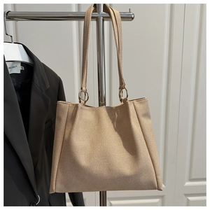 Detail of apricot woven tote bag with circular metal rings and stylish shoulder strap