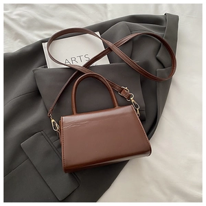 Detail view of brown vintage PU leather handbag texture with gold metal buckles